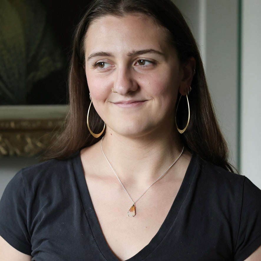 Woman wearing large hoop earrings and natural colored necklace
