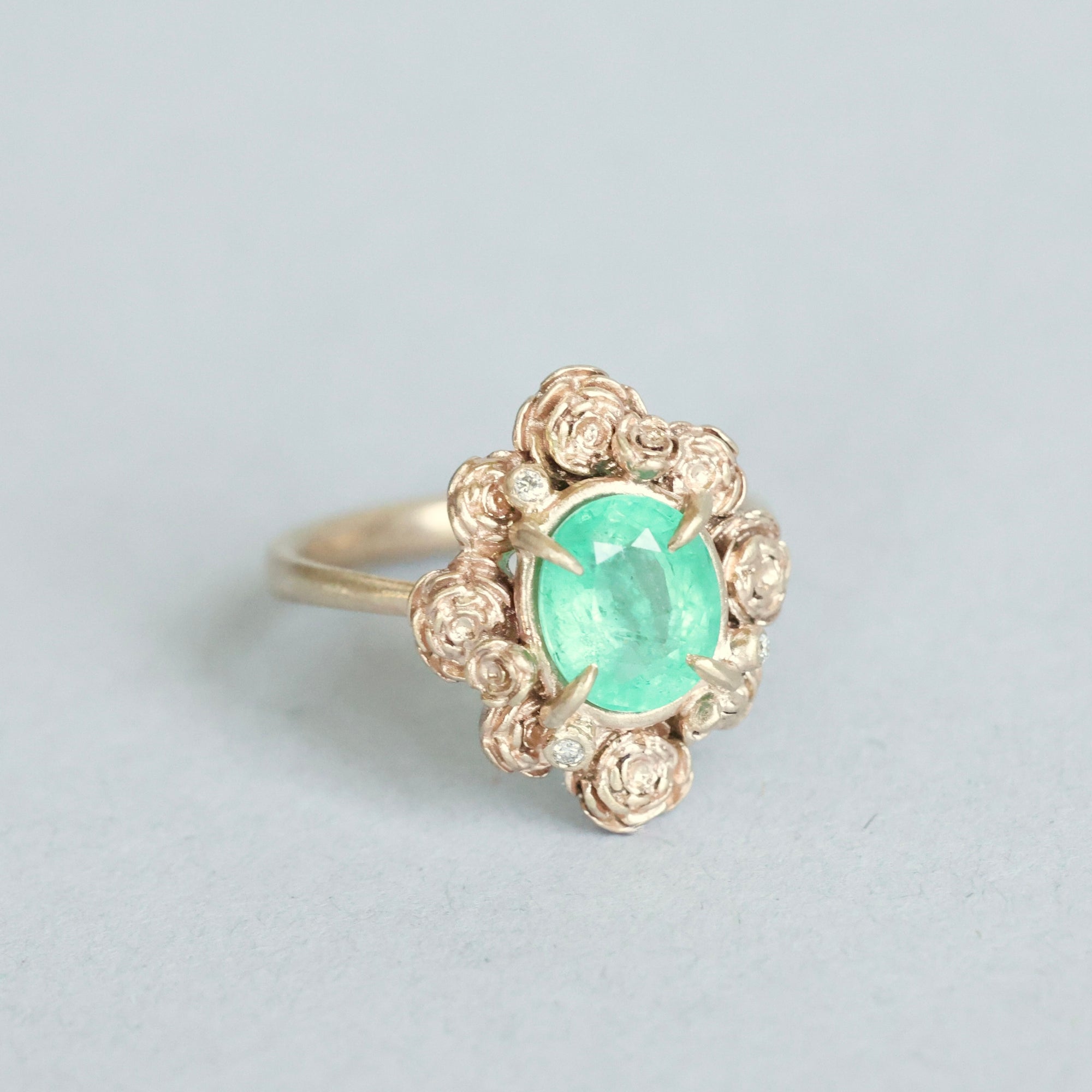 Green stone surrounded by golden rose setting 