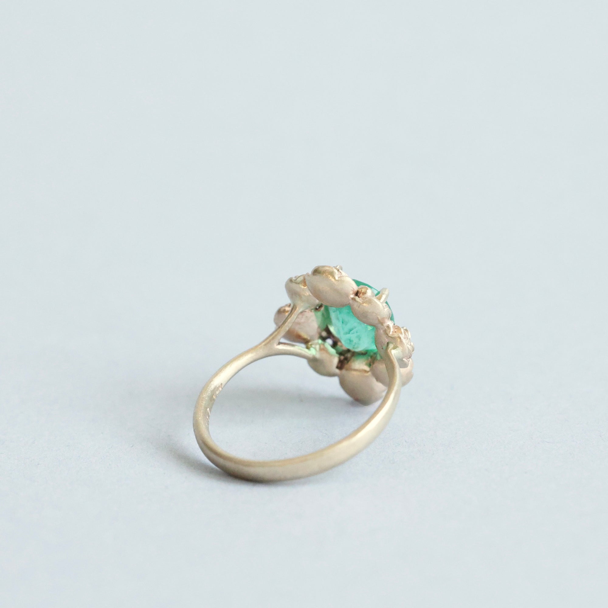 Green stone surrounded by golden rose setting 