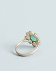 Green stone surrounded by golden rose setting 