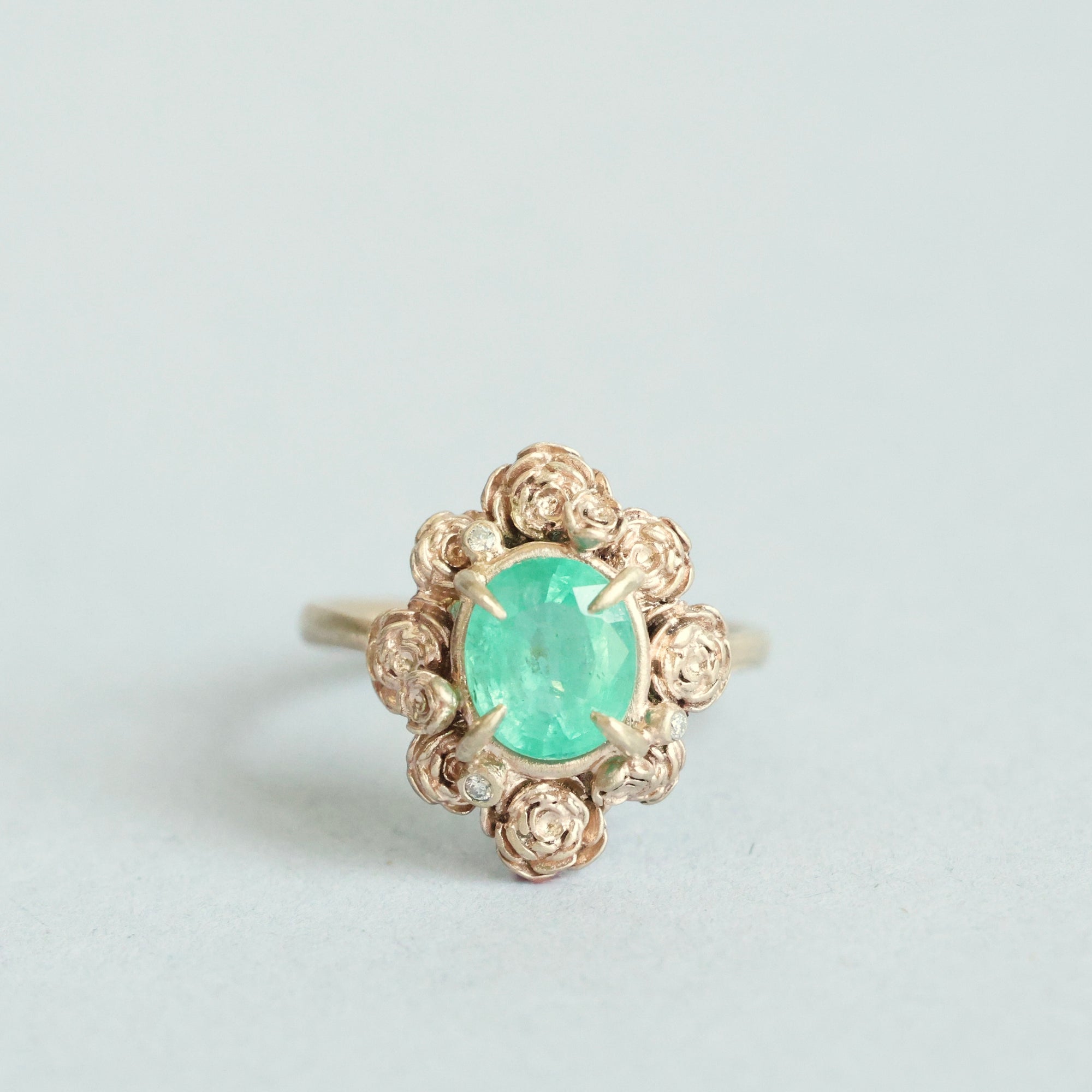 Green stone surrounded by golden rose setting 