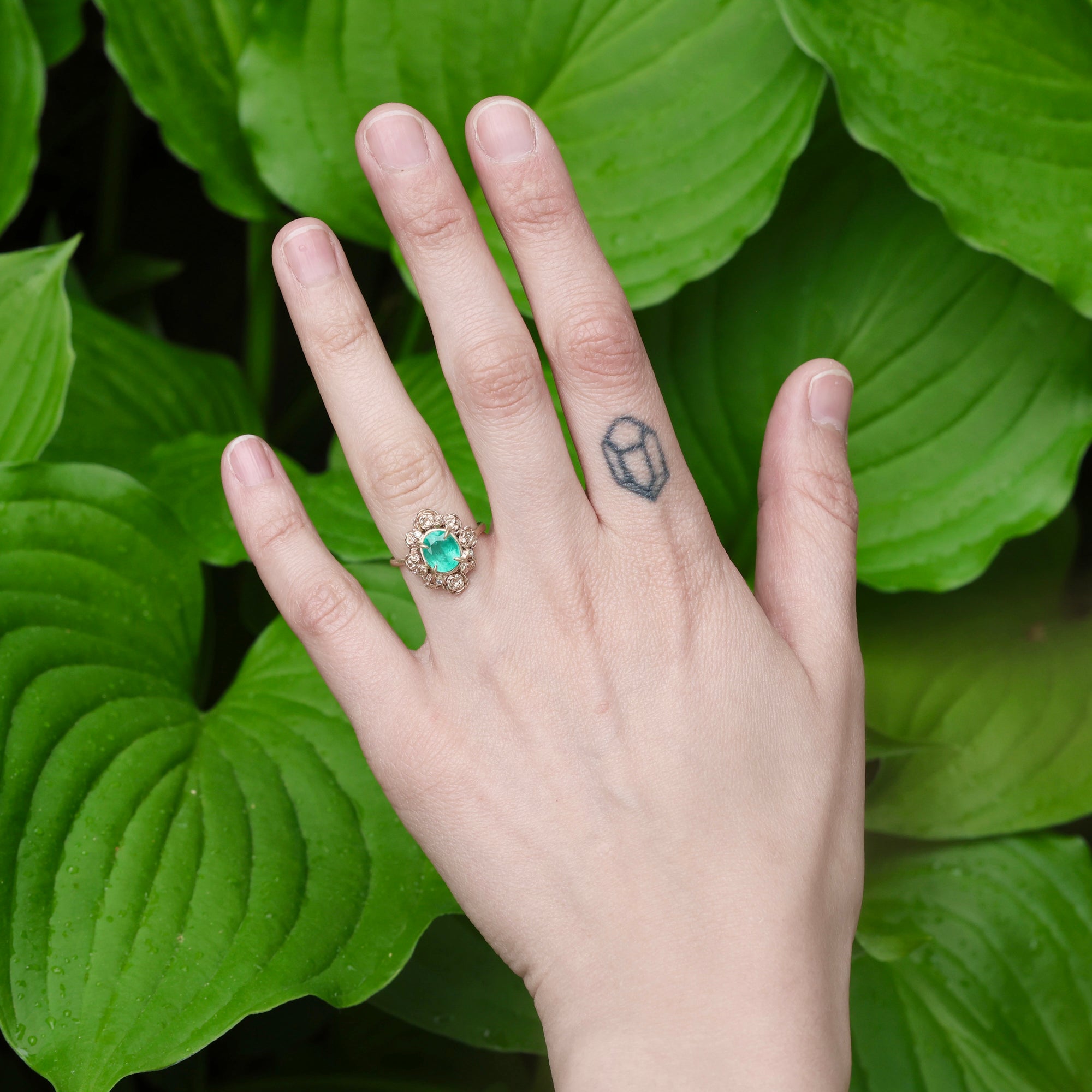 Green stone surrounded by golden rose setting on hand