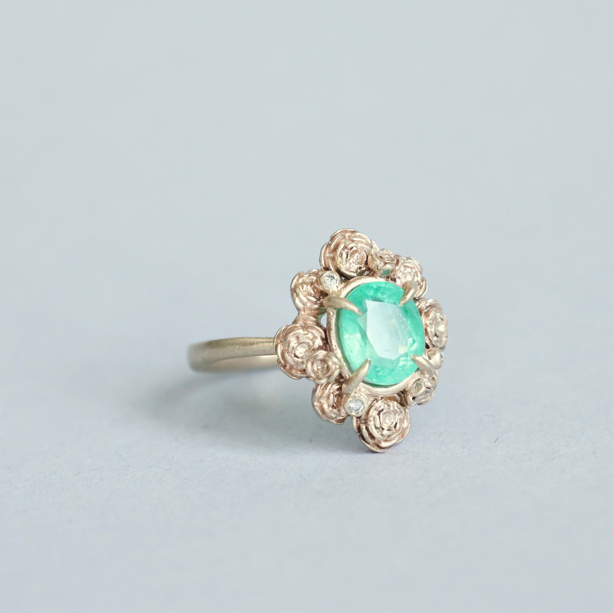 Green stone surrounded by golden rose setting 