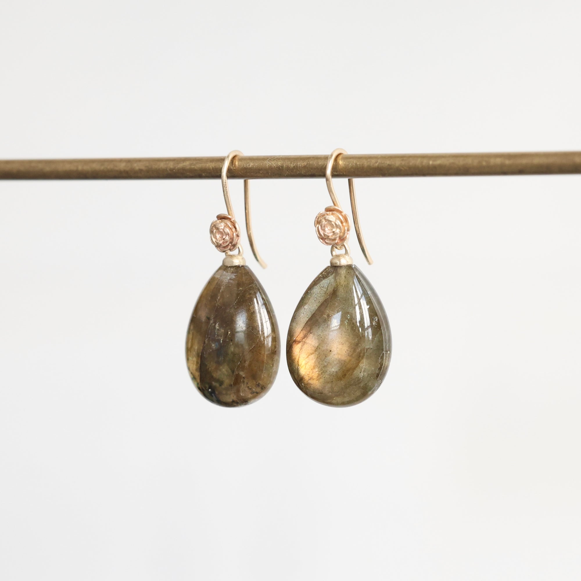 Teardrop-shaped earrings with gold hooks on a white background