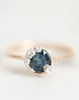 Ring with dark blue stone and lots of barnacles against plain background.