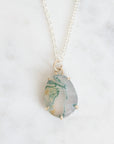 Necklace with a pendant featuring a green and white marbled stone on a light background