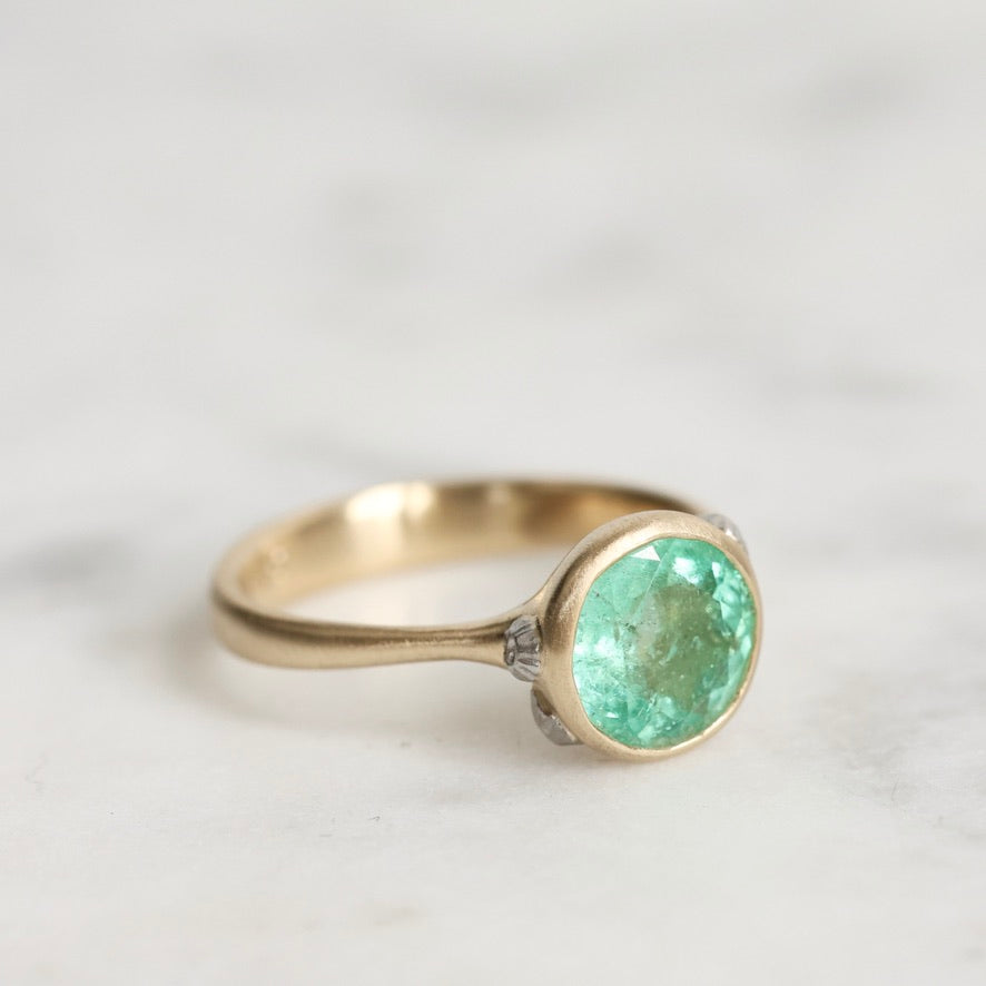 Gold ring with a green gemstone on a light background