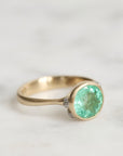 Gold ring with a green gemstone on a light background
