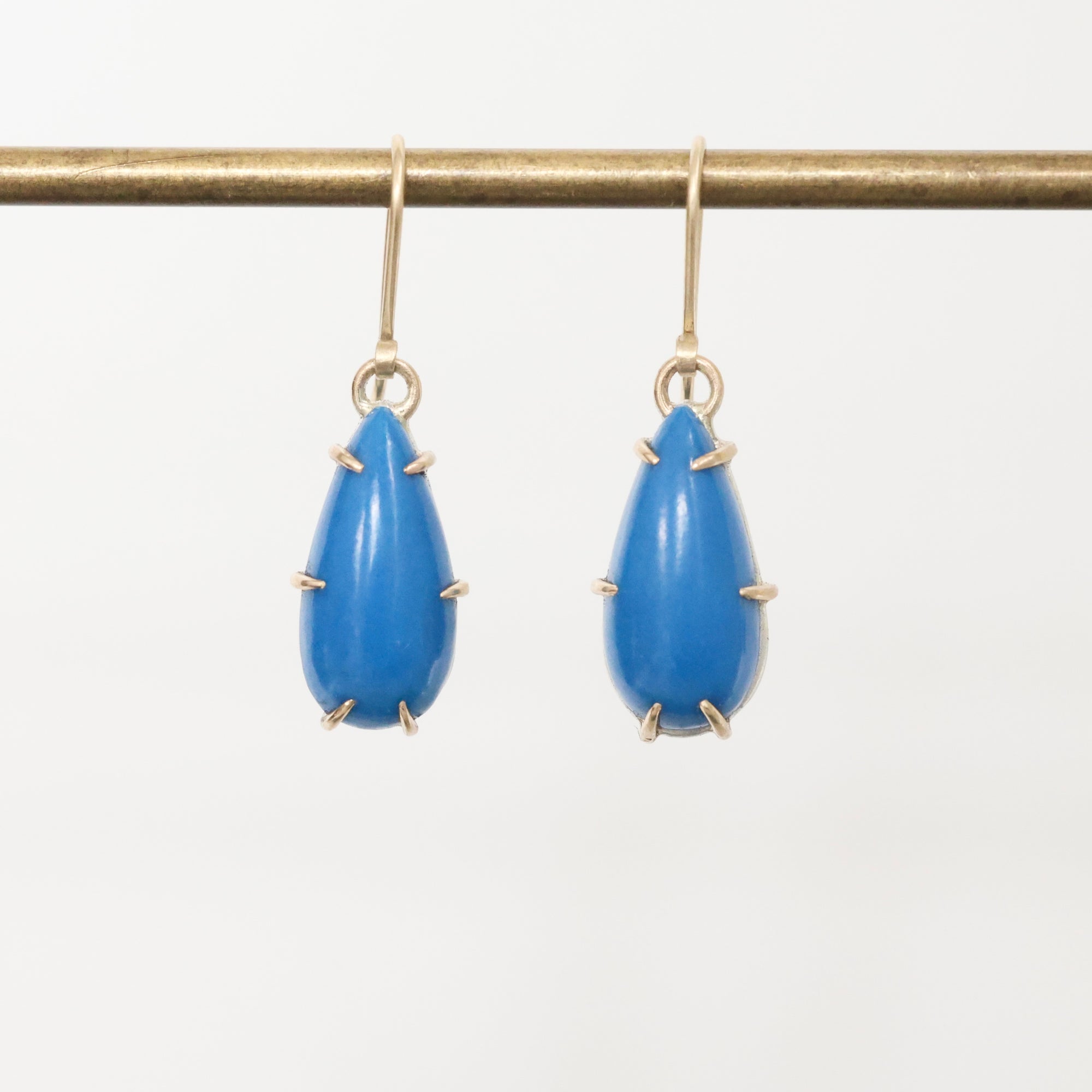 Blue teardrop earrings with gold accents on a white background
