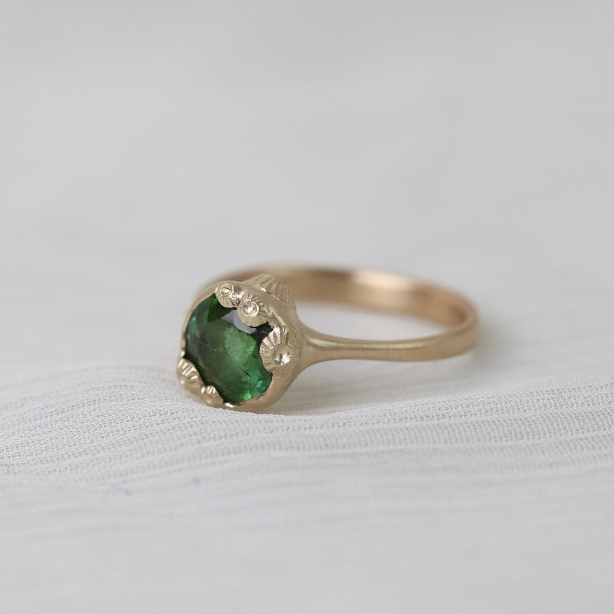 Gold ring with green gemstone on a white background