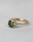 Gold ring with green gemstone on a white background