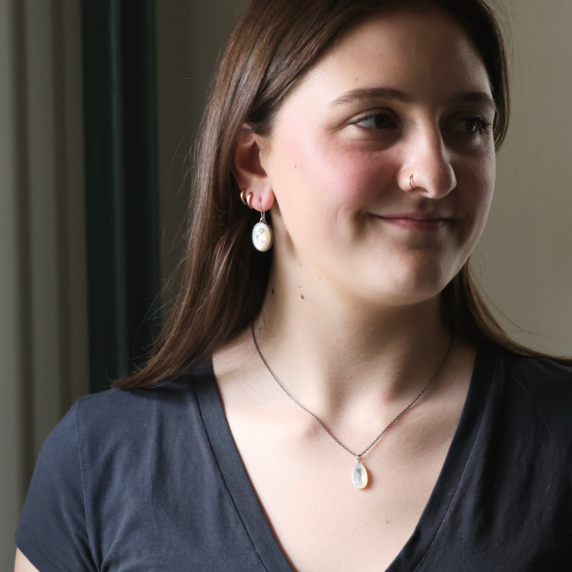 Woman wearing earrings and a necklace with a neutral background