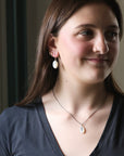 Woman wearing earrings and a necklace with a neutral background