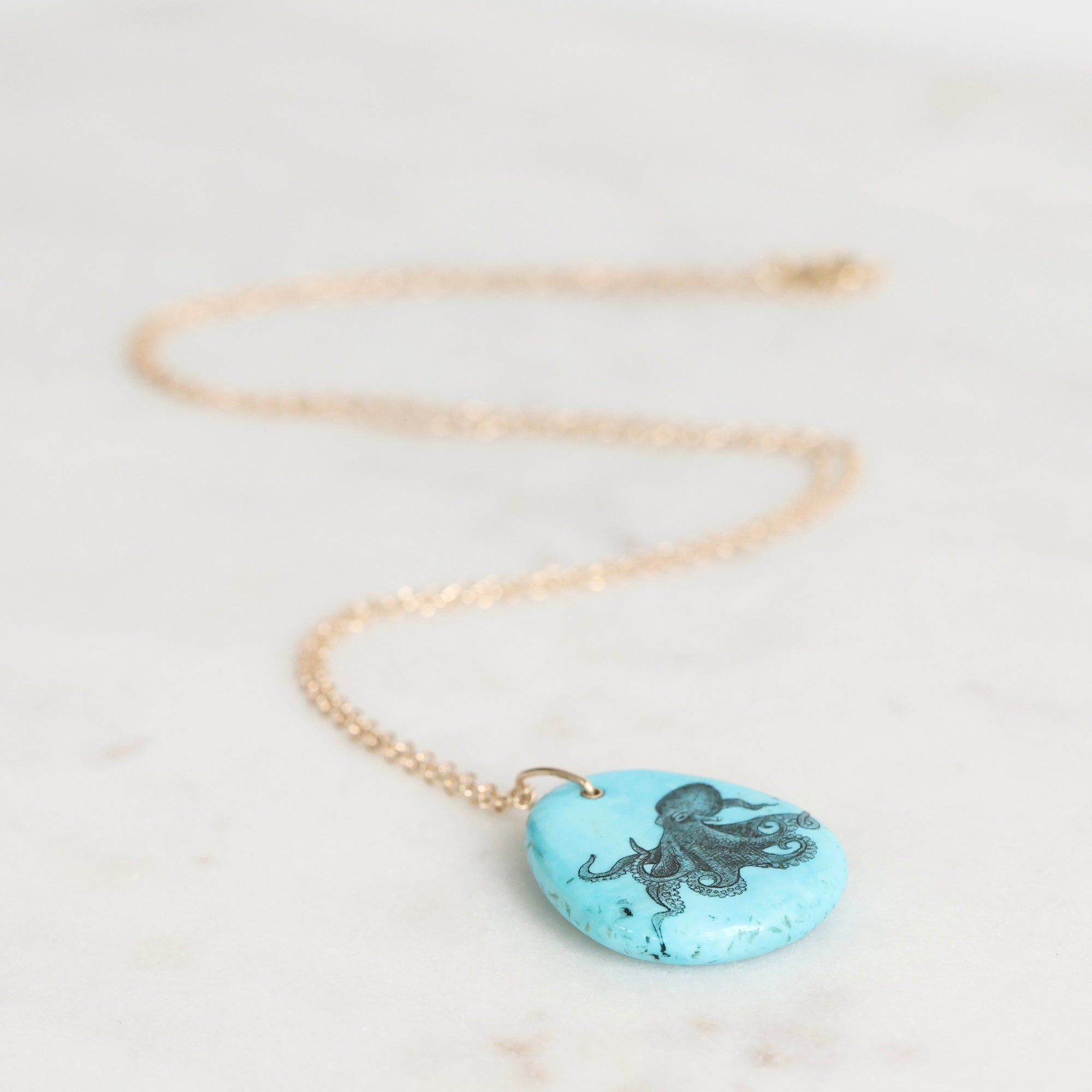 Necklace with a turquoise pendant featuring an octopus design on a light background