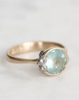 Gold ring with a light blue gemstone on a white background