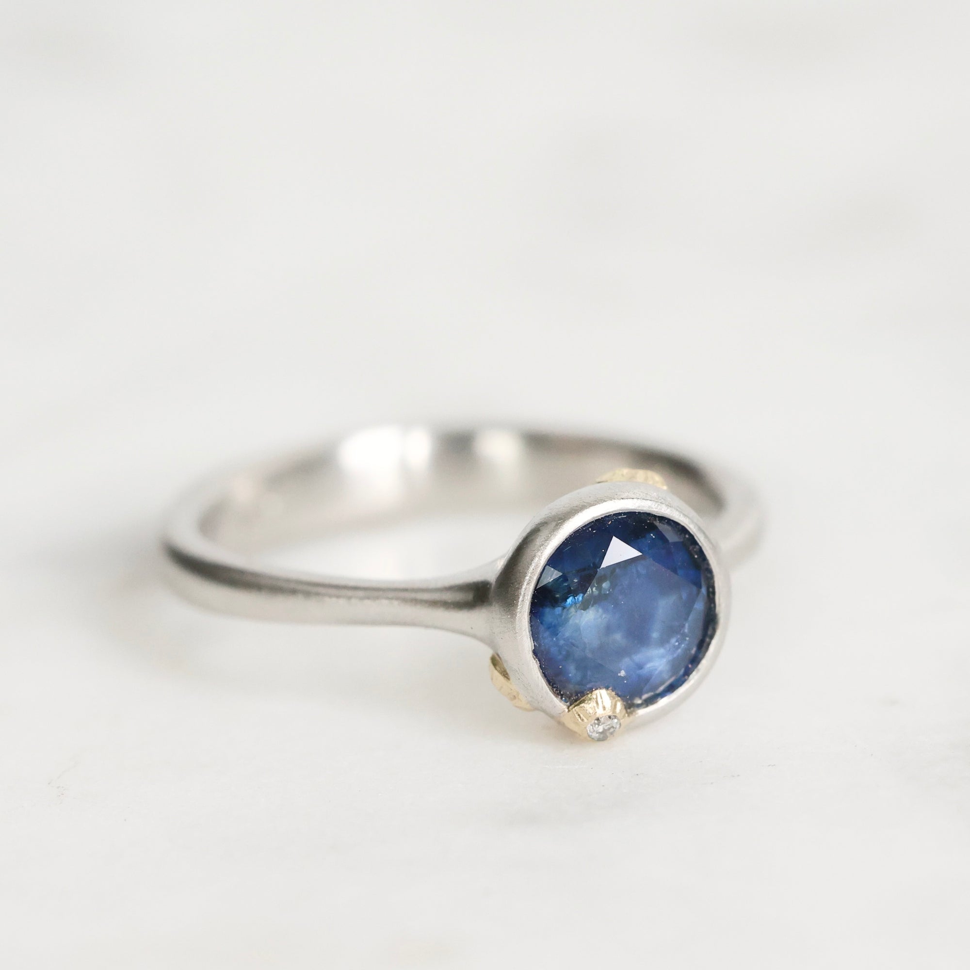 Silver ring with a blue gemstone on a light gray background