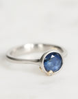 Silver ring with a blue gemstone on a light gray background