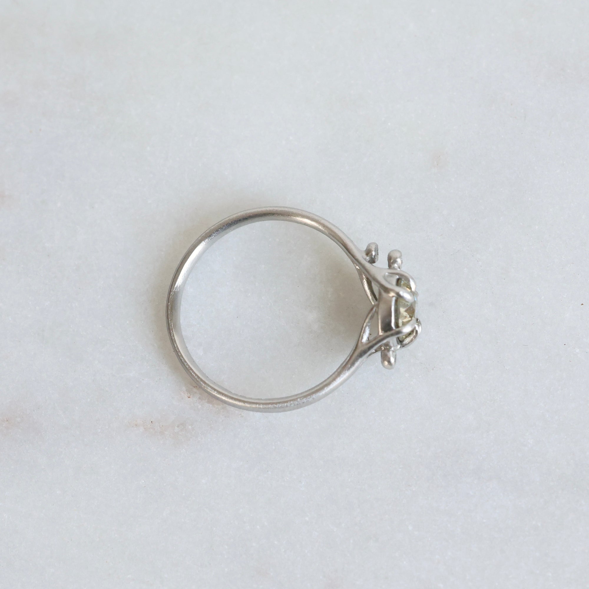 Silver ring with a diamond on a light gray background