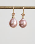 Pair of pink pearl earrings with gold clasps on a light gray background