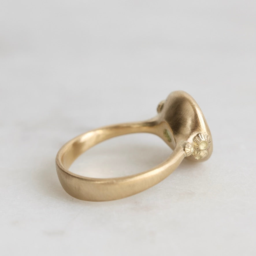 Gold ring with a small decorative element on a light gray background