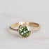 Gold ring with a green gemstone on a light gray background