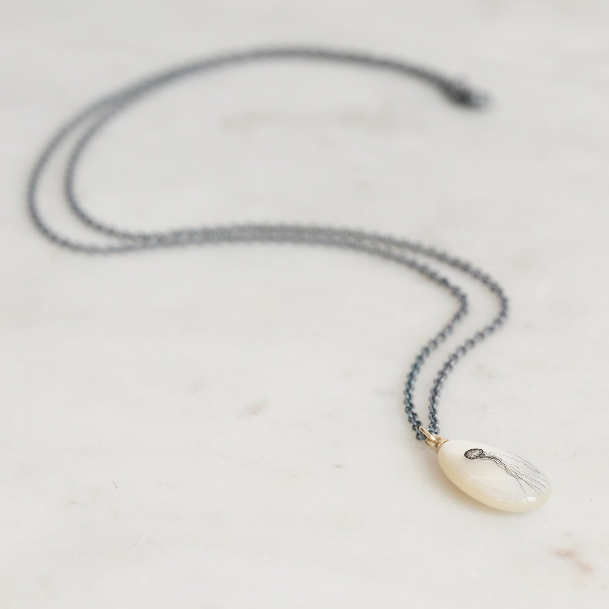 Necklace with a white pendant on a light gray background