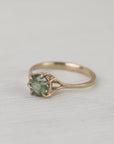 Gold ring with a green gemstone on a light fabric background