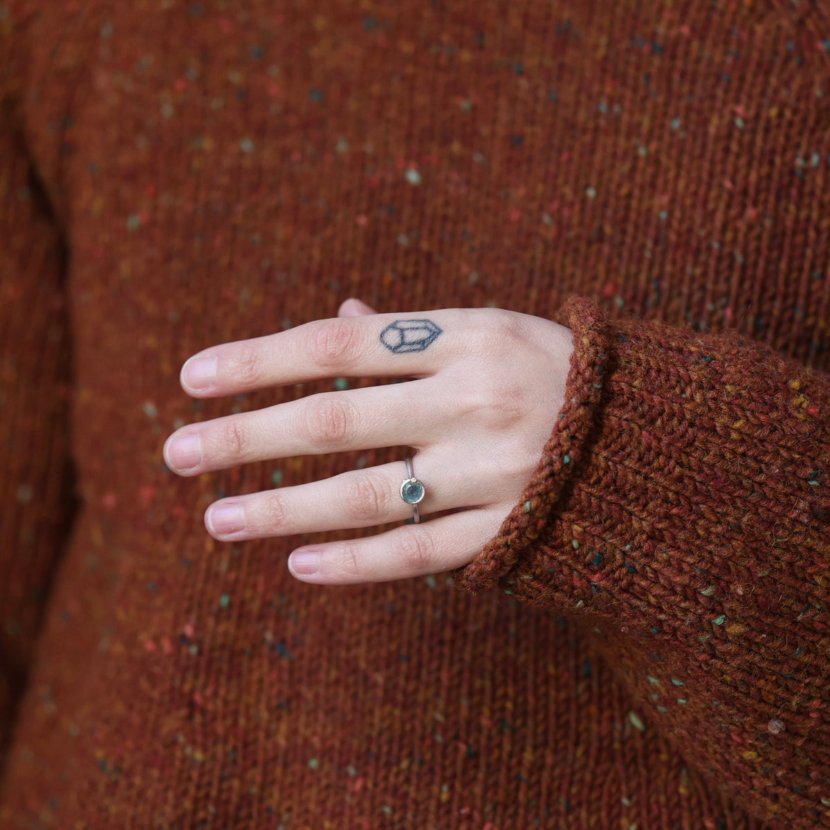Hand wearing blue gemstone ring. 