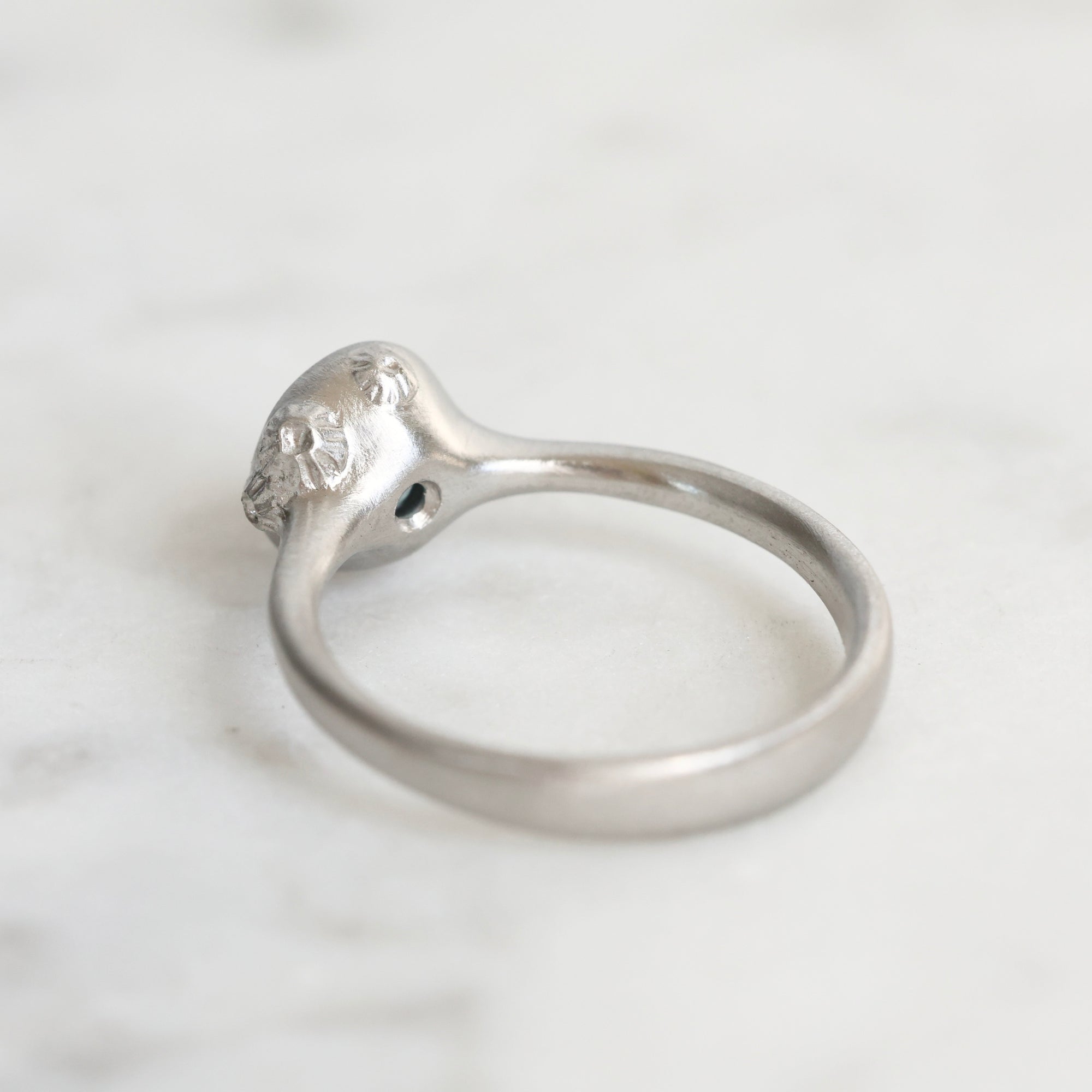 Silver ring with a small diamond on a light gray background