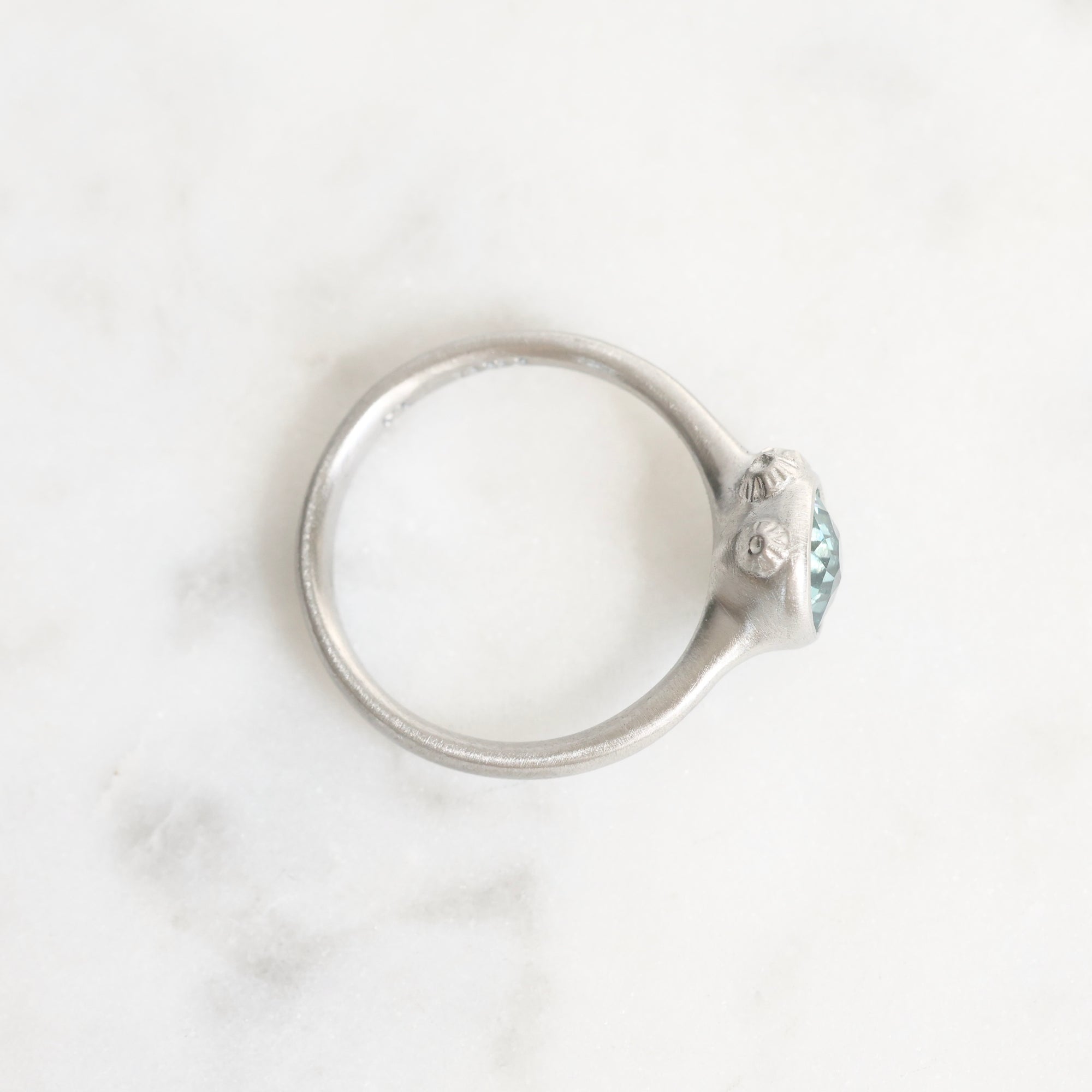 Silver ring with a small gemstone on a light gray background
