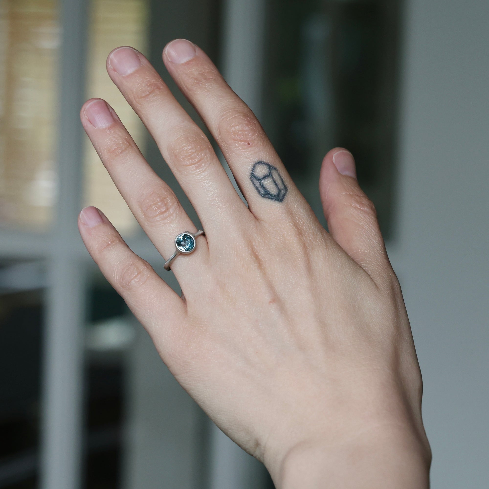 Hand with a ring and a small tattoo on a blurred background