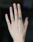 Blue stone ring on hand with tattoo. Center stone is surrounded by diamond berries. 