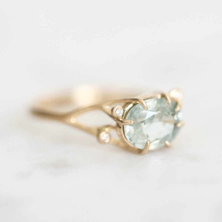 gemstone ring set east west in branchy prongs. Little diamond accents surround the center stone