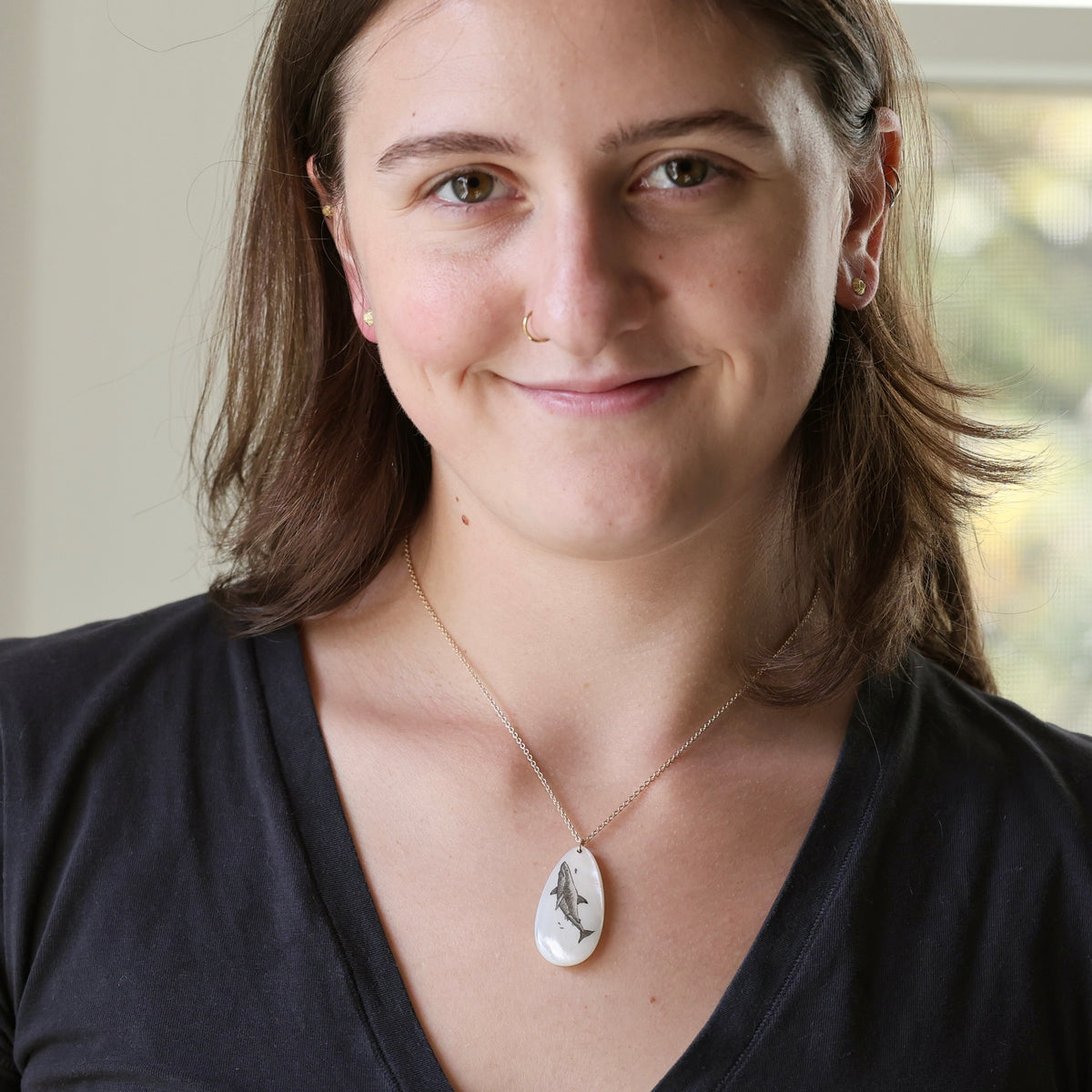 Woman wearing necklace with large mother of pearl pendant with a great white shark