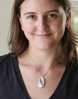 Woman wearing necklace with large mother of pearl pendant with a great white shark