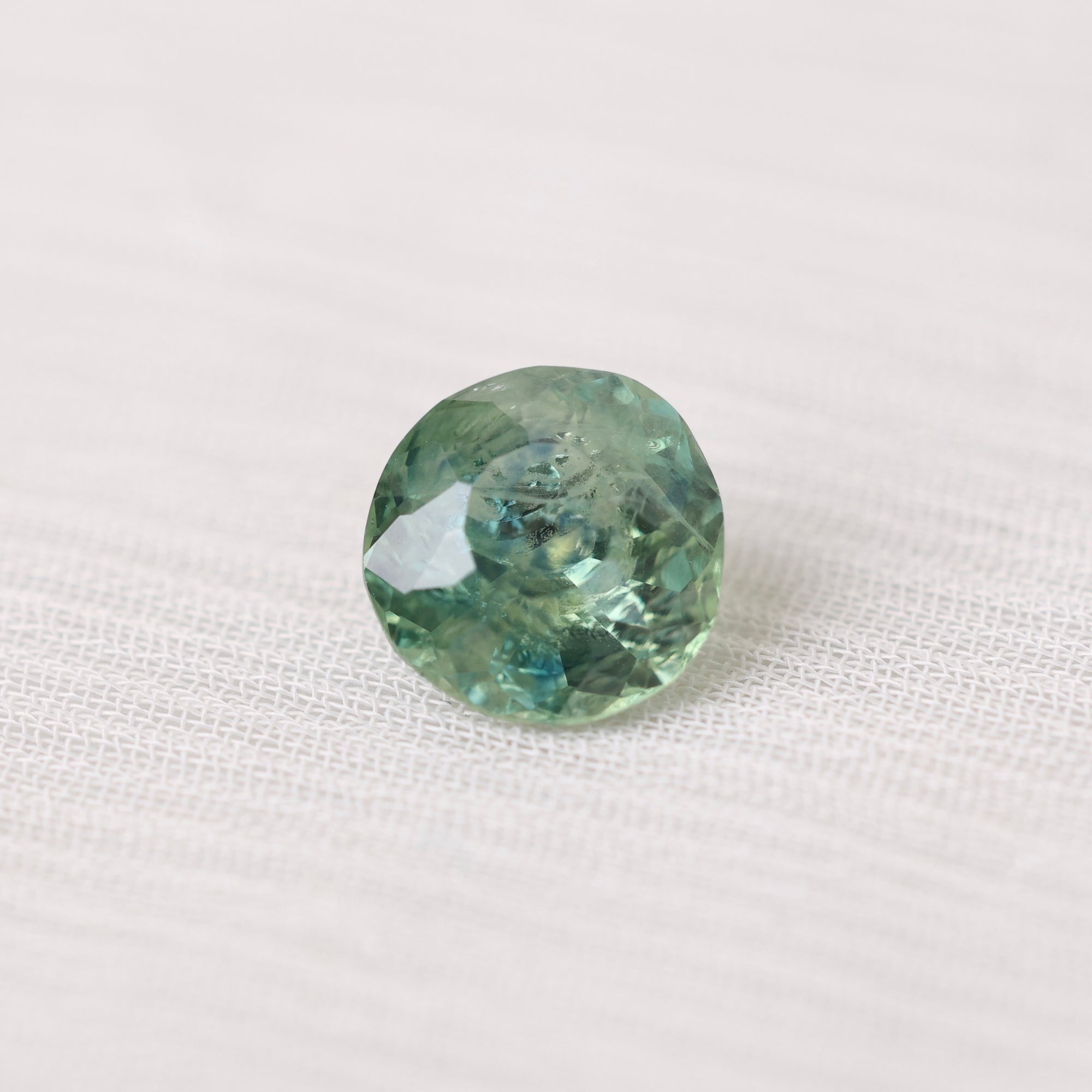 Green gemstone on a white fabric background