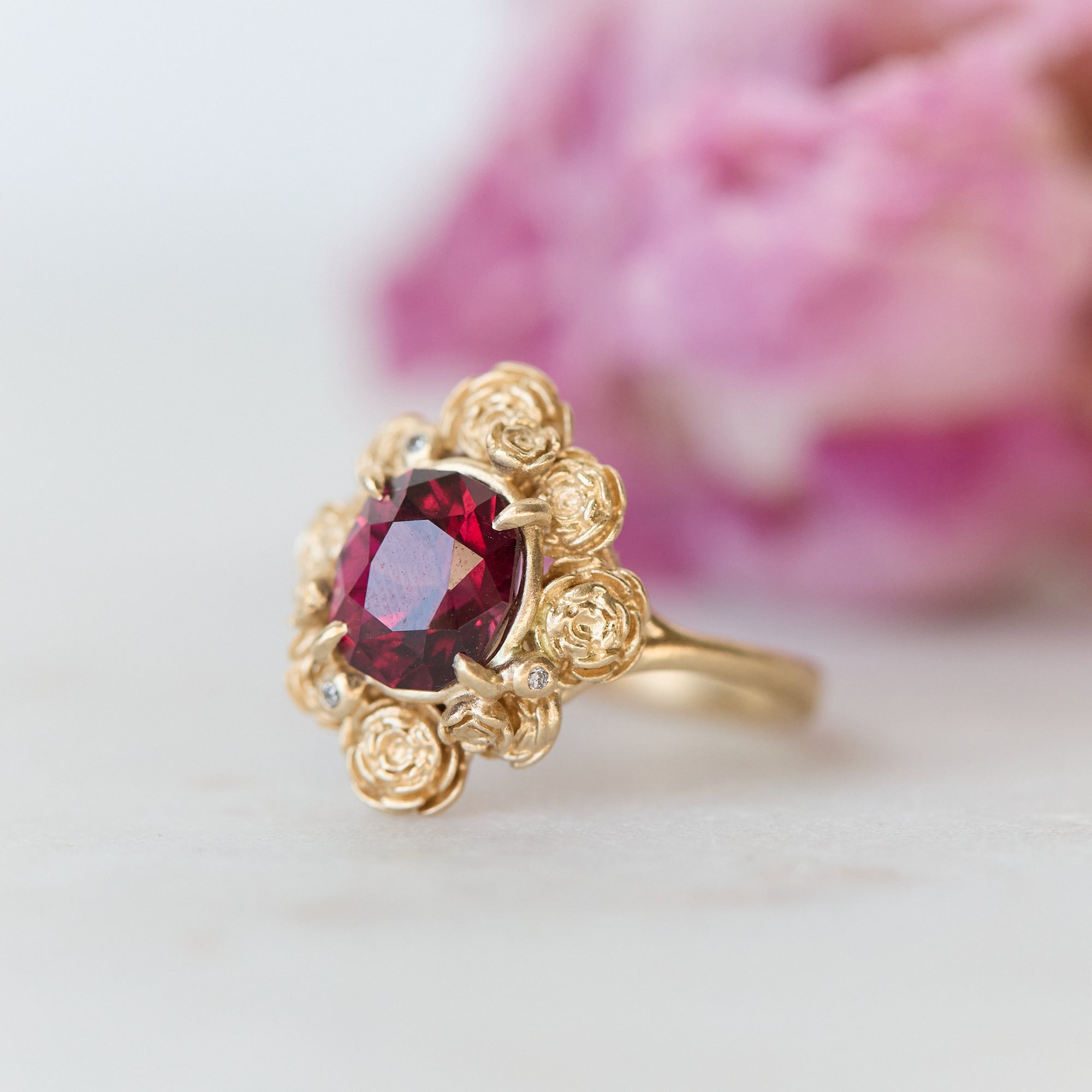 Gold ring with a red gemstone on a light background