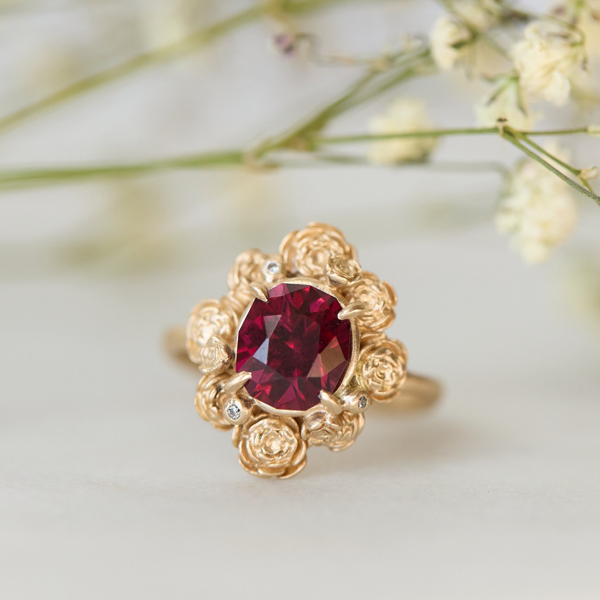 Gold ring with a red gemstone on a light background