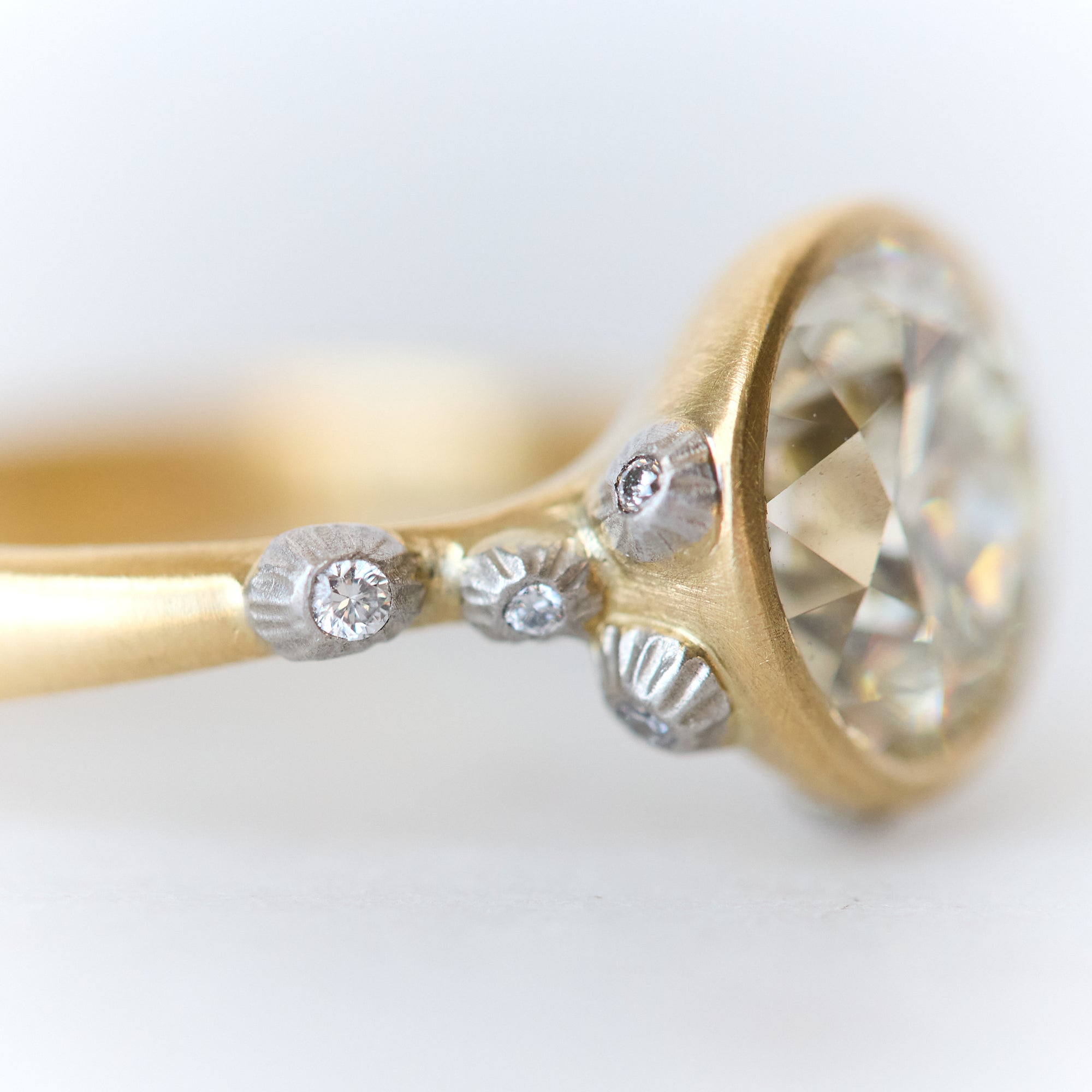 Gold ring with a large diamond and smaller diamonds on a light background