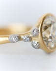 Gold ring with a large diamond and smaller diamonds on a light background