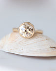 Gold ring with a large gemstone on a shell against a light background
