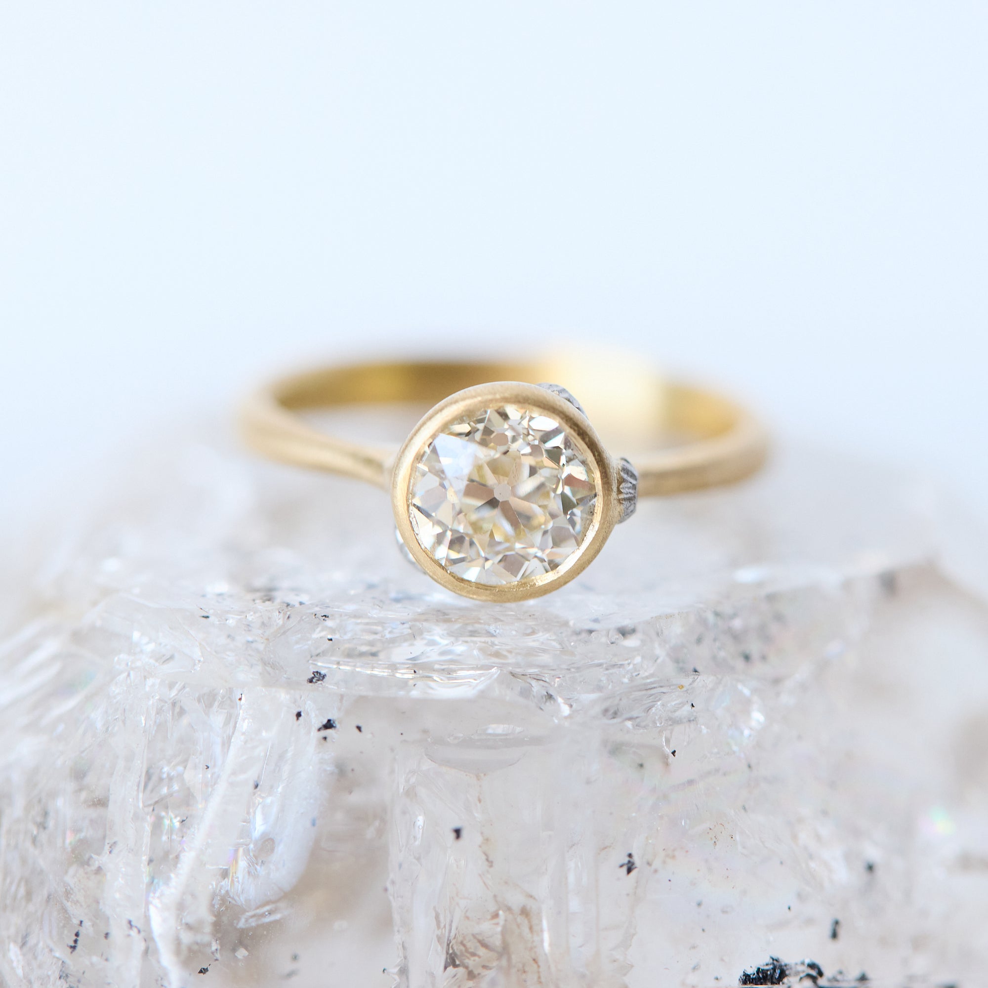 Gold ring with a diamond on a textured white surface