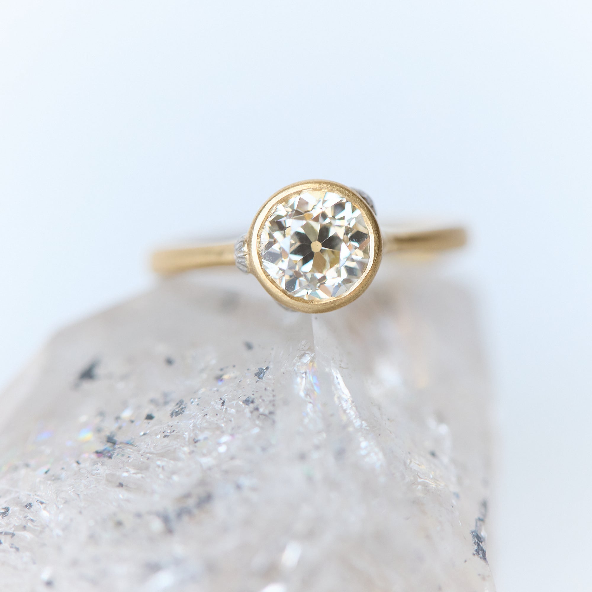 Gold ring with a diamond on a textured white surface