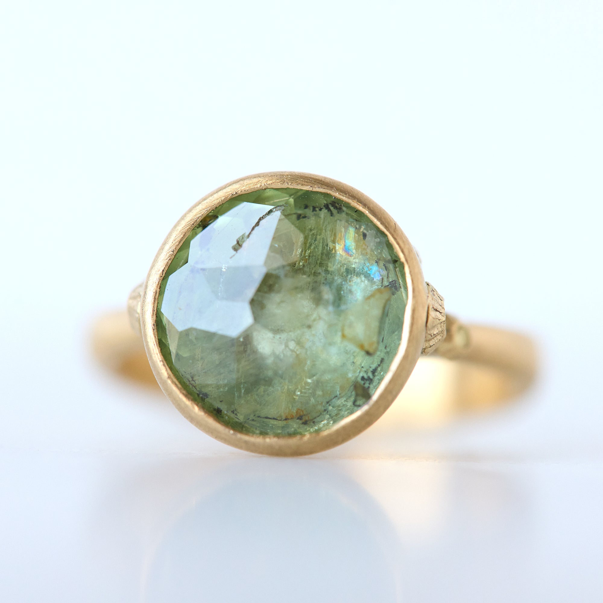 Gold ring with a green gemstone on a white background