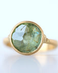 Gold ring with a green gemstone on a white background