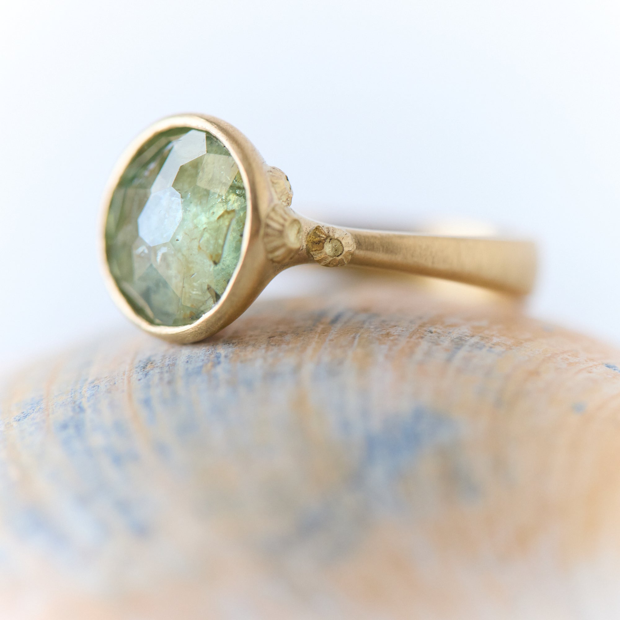 Gold ring with a green gemstone on a marble surface