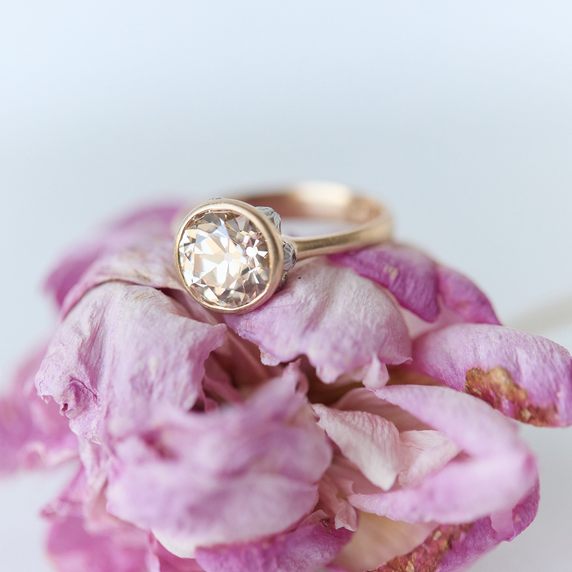 Gold ring with a large diamond on pink floral petals
