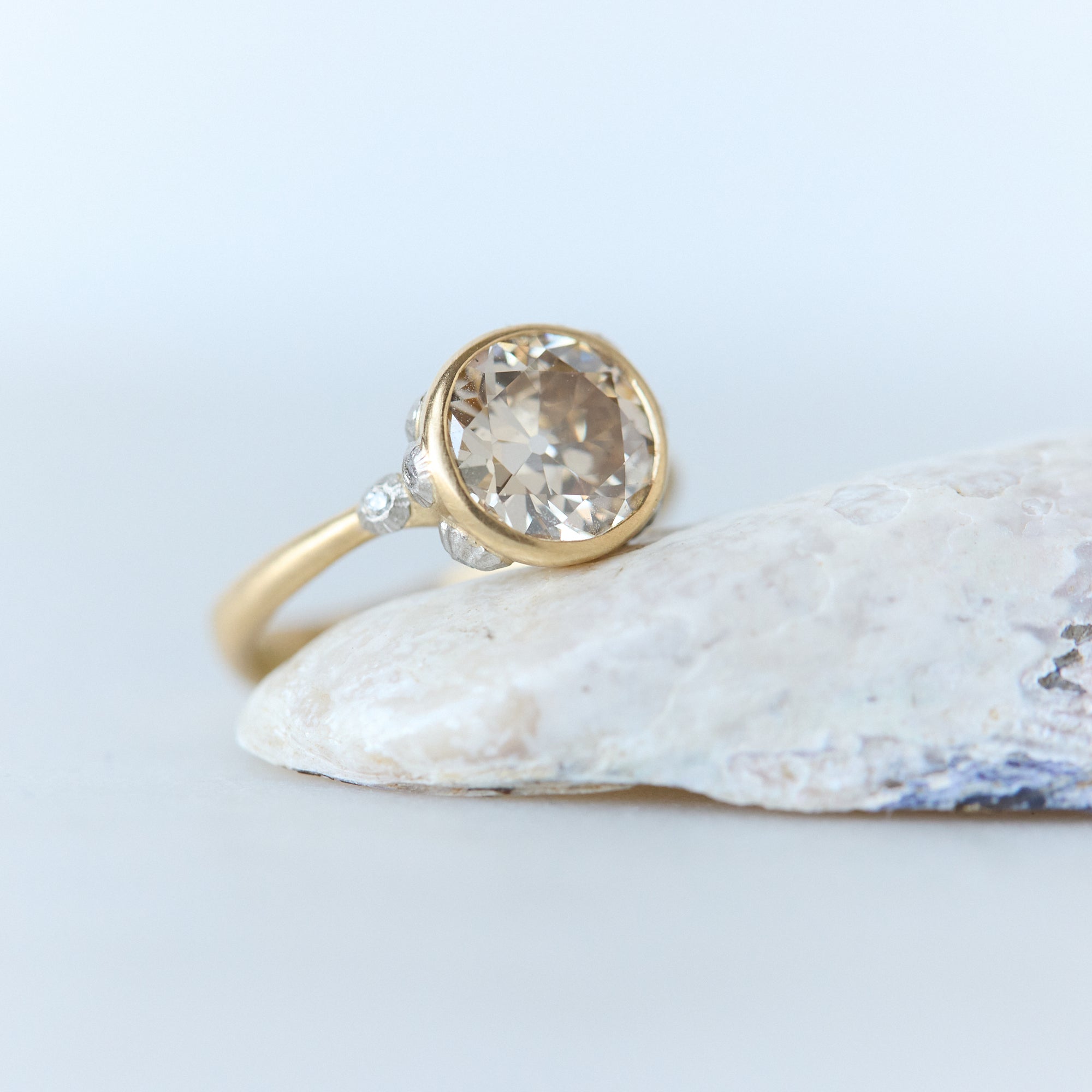 Gold ring with a large gemstone on a light blue background