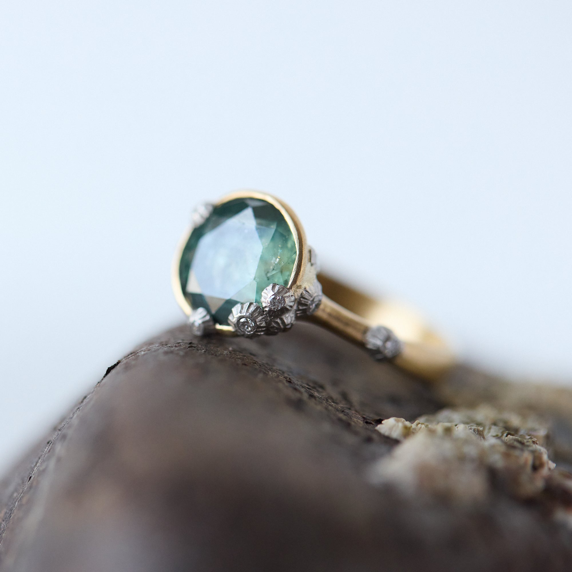 Gold ring with a green gemstone on a textured surface