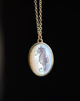 Necklace with a pendant featuring a seahorse design on a dark background